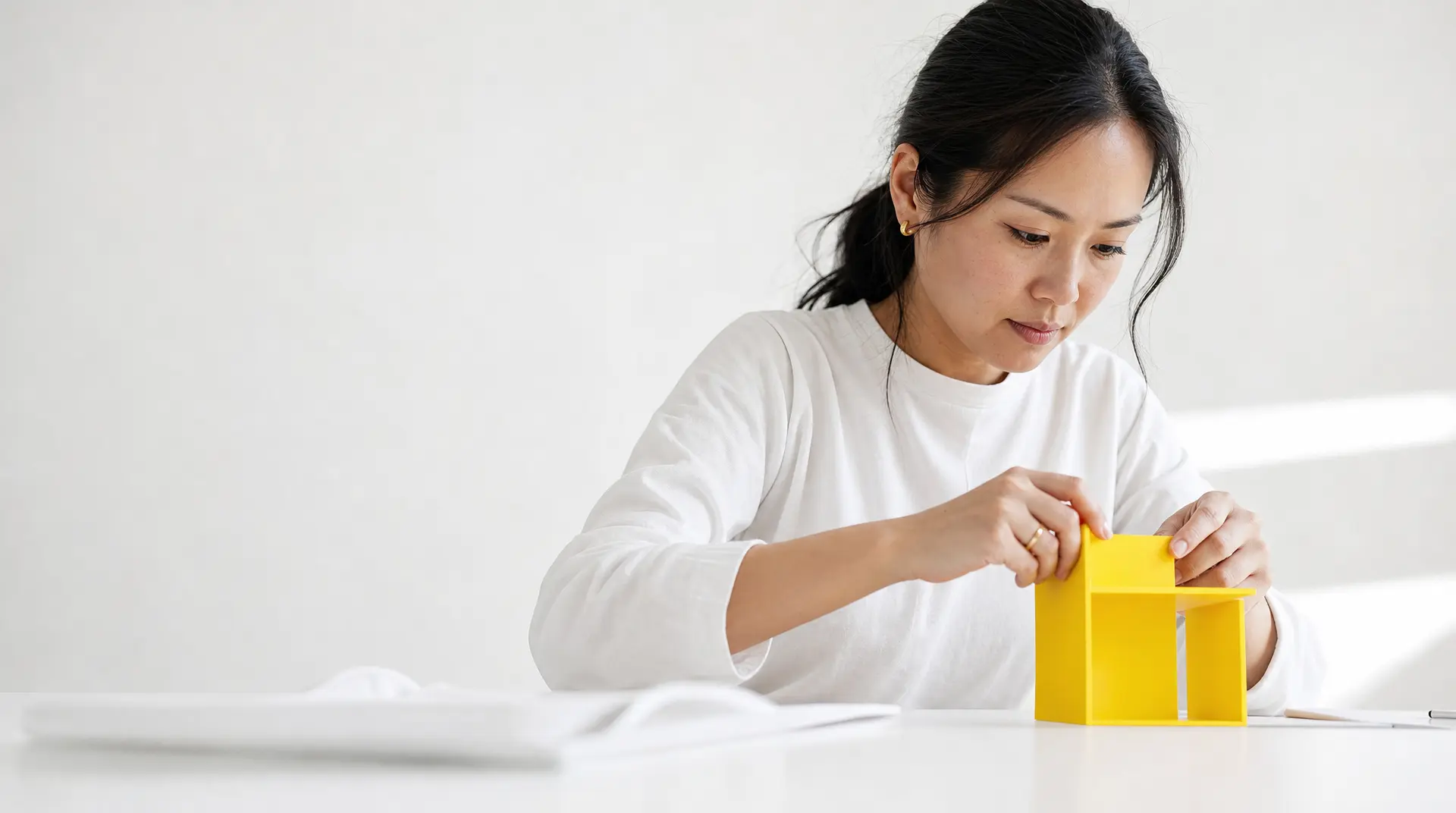 A person in a white shirt carefully tapes a bright yellow shipping box on a clean table, building brand visibility through every order.